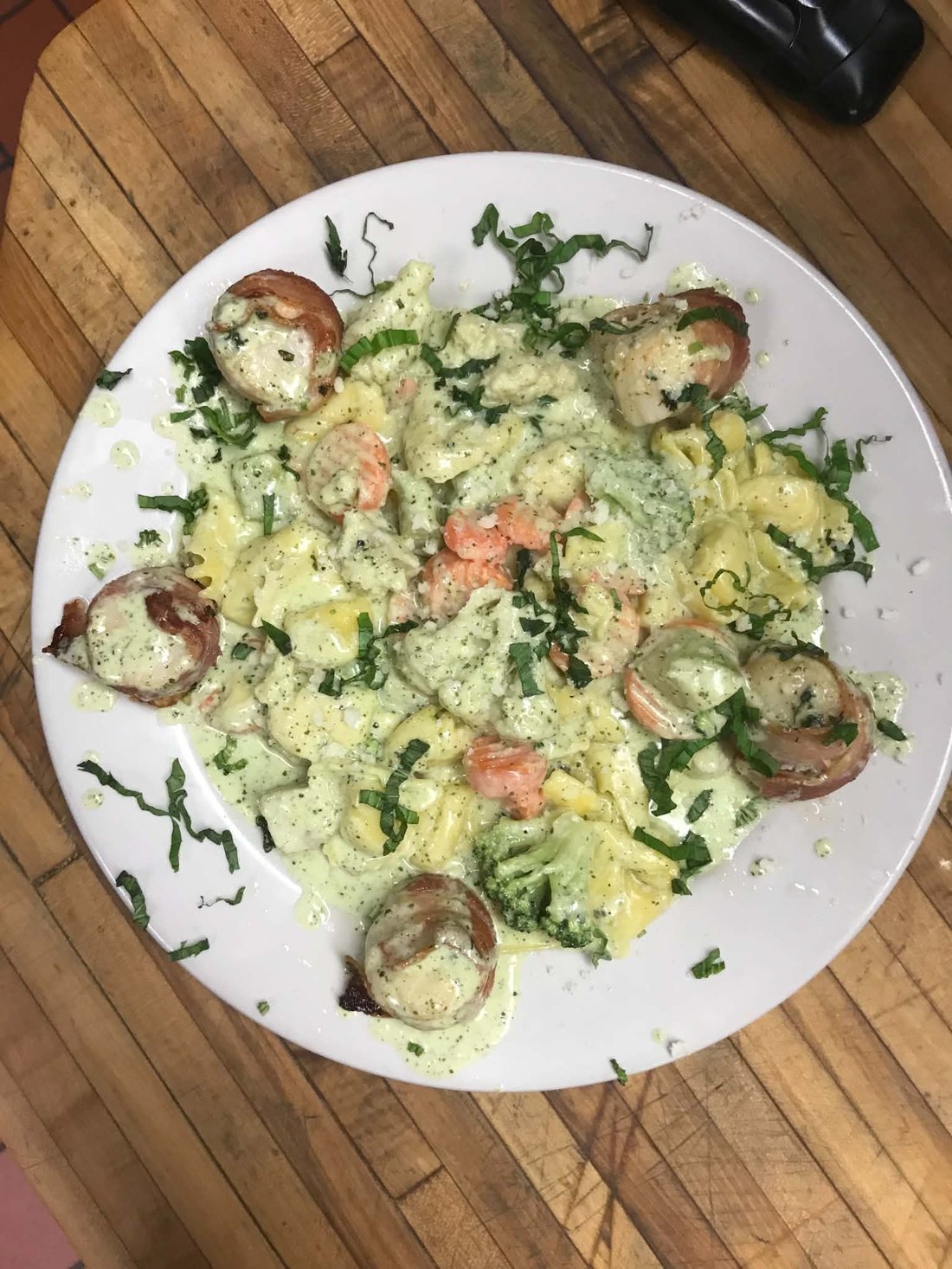 Bacon-wrapped scallops over pesto pasta with shrimp